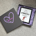 Gymnastics-themed gift box with 'it's a gymnast thing' and 'Eat Sleep Gymnastics Repeat' framed gymnastics print.