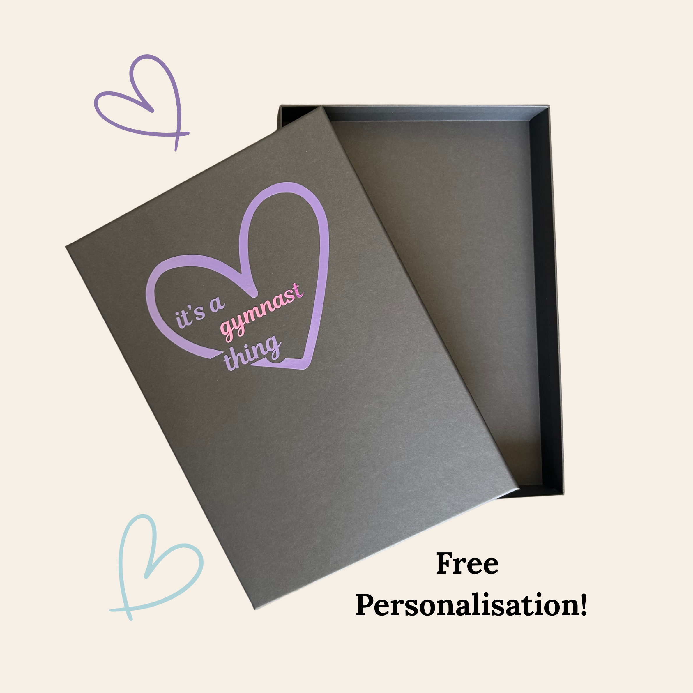 Grey gymnastics gift box with purple heart and text 'it's a gymnast thing' on a beige background